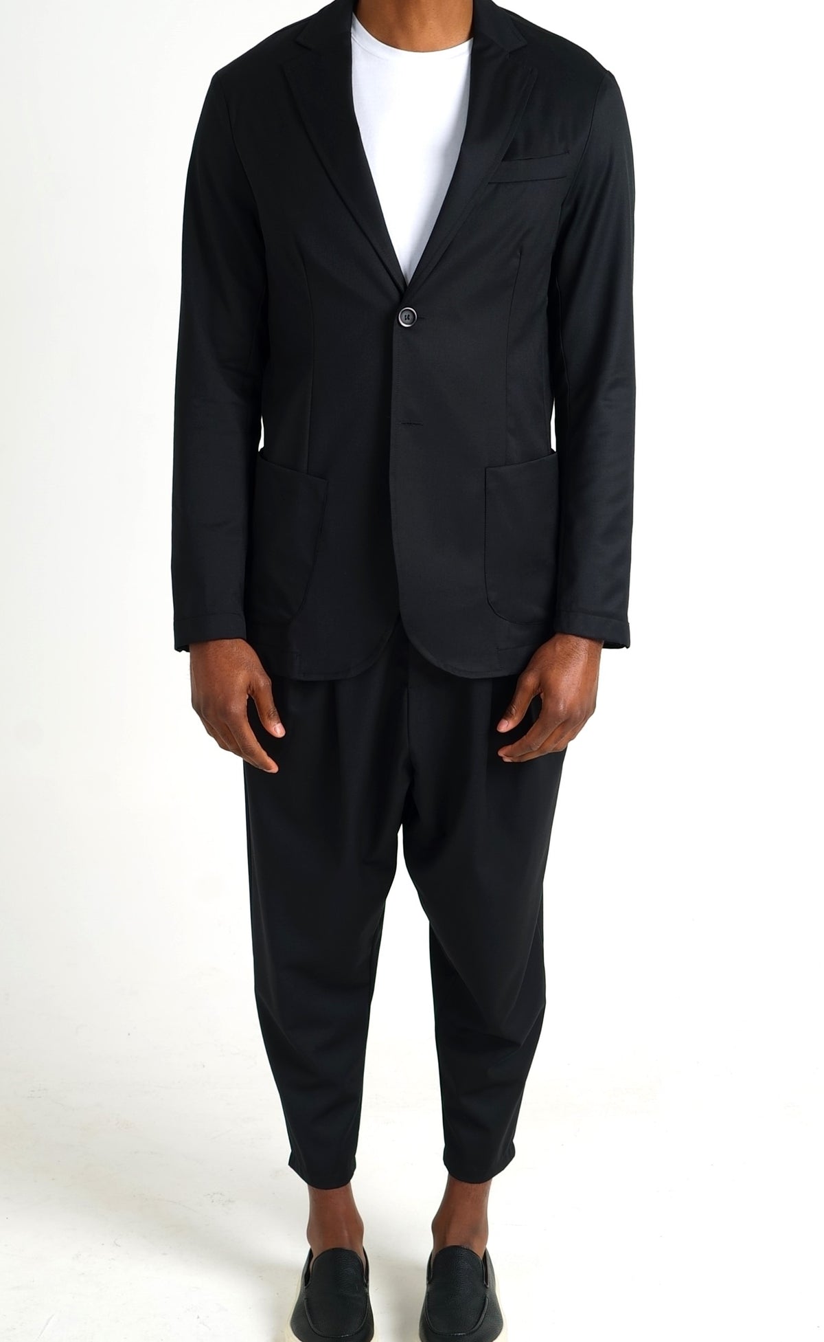 Costume d'été homme noir, veste et pantalon à pinces portés avec un t-shirt blanc