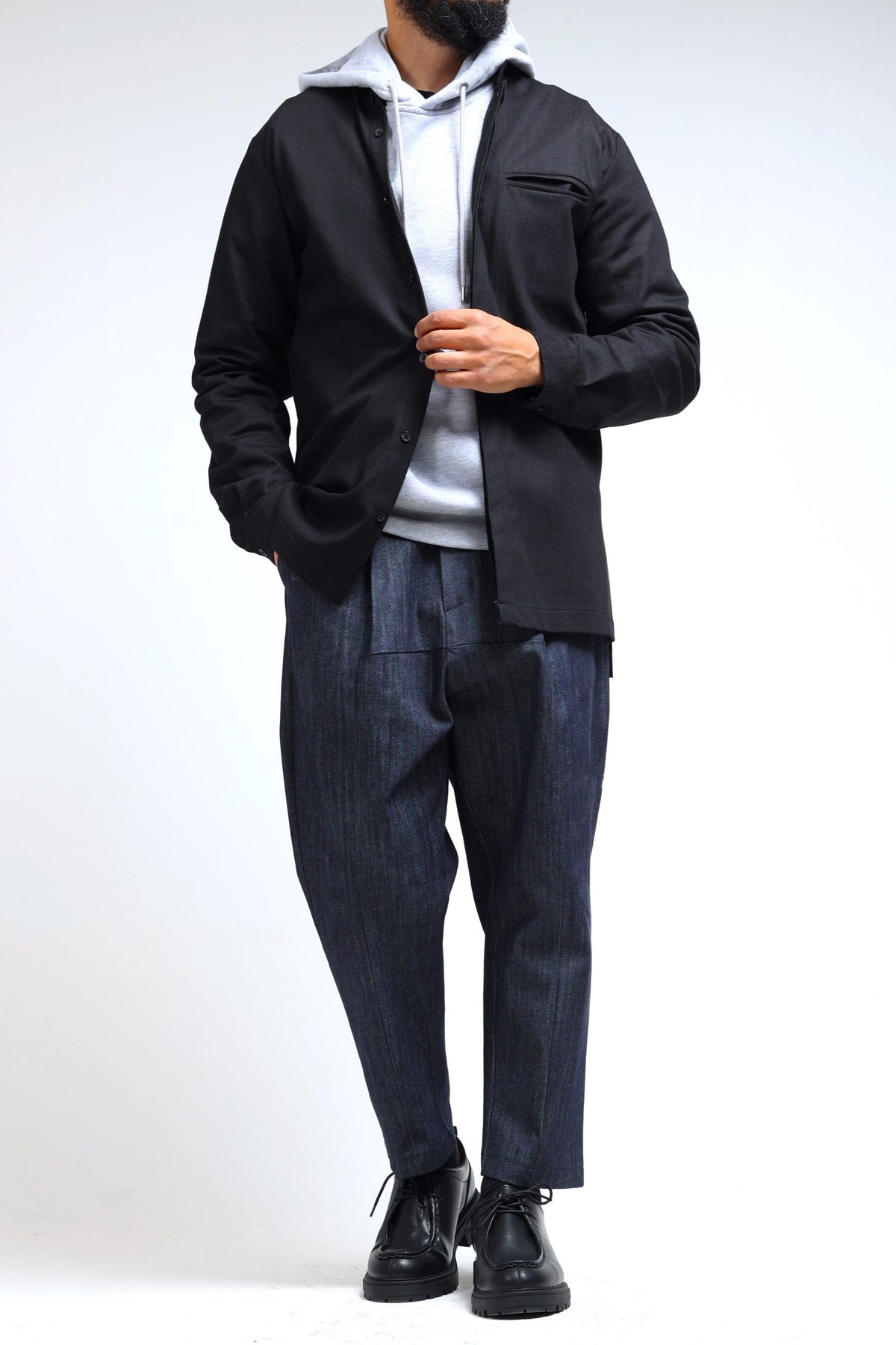 Sarouel en jean NewFit bleu brut porté avec une veste noire et un hoodie
