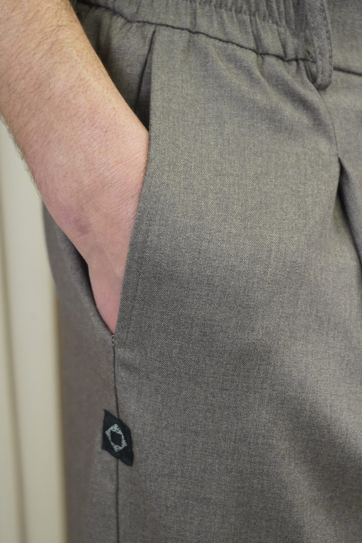 Détail de la poche et du logo du pantalon Dunes marron glacé