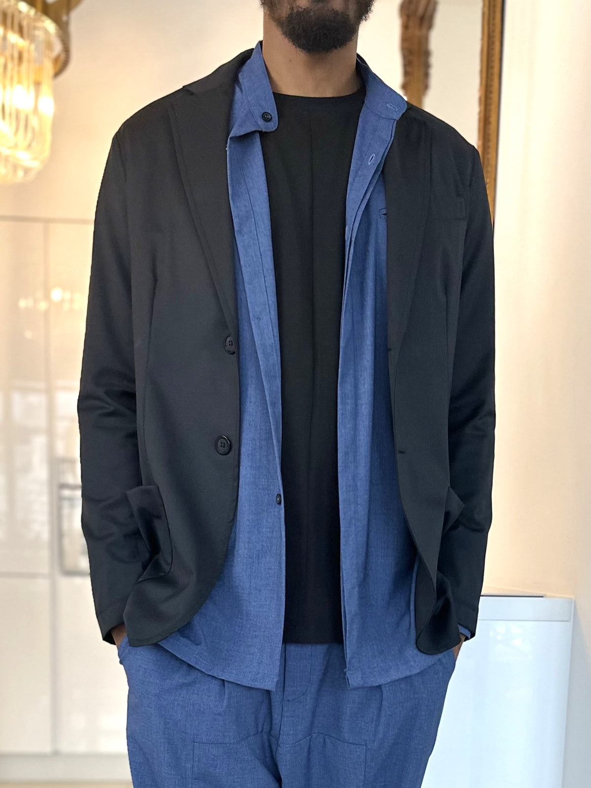 Veste de costume d'été homme noire portée ouverte sur un ensemble bleu