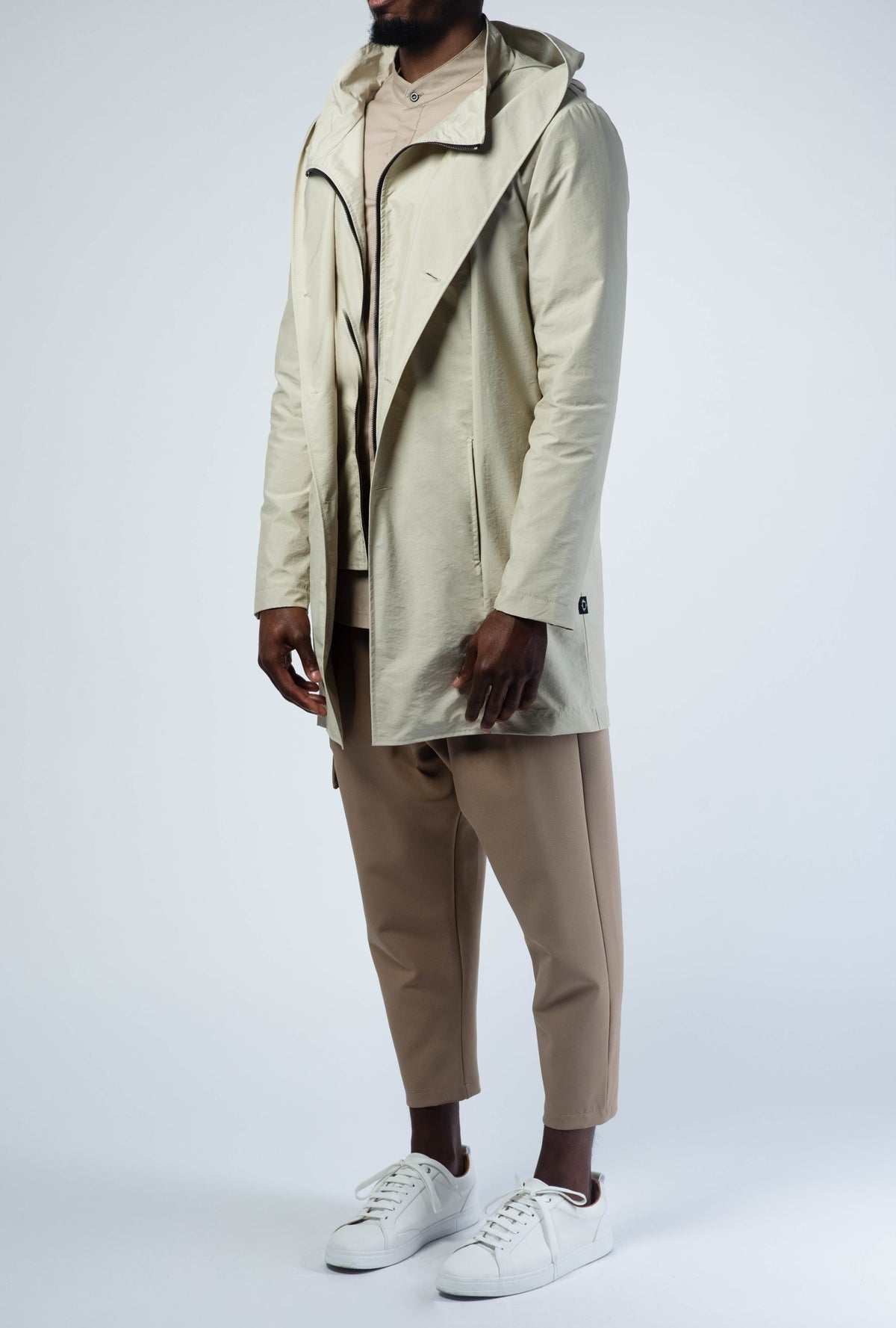 Parka homme beige crème à capuche portée avec un pantalon beige